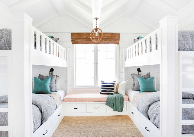 Bunk Room. White Bunk room with white bunk bed with gray bedding, turquoise decorative pillows, rope lighting, bamboo shades, window seat, sisal carpeting and shiplap walls. Bunk beds with storage under beds. #Bunkroom
