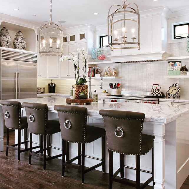 White kitchen love! White kitchen island stools. Stools were purchased from Crate & Barrel, we had them custom re-upholstered. We also added the nail heads and ring hardware to dress them up a bit! The pendants are from Visual Comfort. #WhiteKitchen Spinnaker Development.