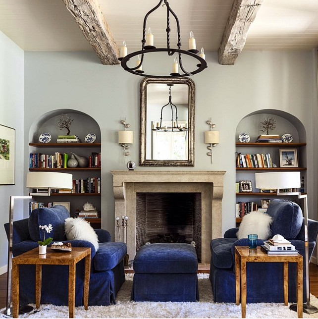Bookshelves on both sides of fireplace. Living room with Bookshelves on both sides of fireplace. Bookshelves on both sides of fireplace, navy velvet couches facing each other and grey walls. Collins Interiors. 