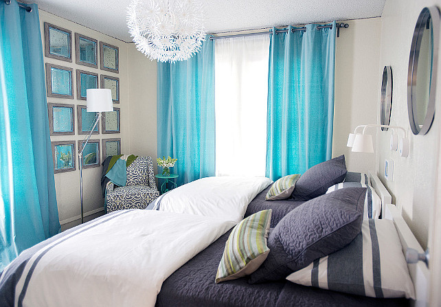 Shared Bedroom. Shared Bedroom Furniture Ideas. Turquoise and navy kids' bedroom features metal convex mirrors illuminated by white sconces placed over a pair of white lacquered twin beds dressed in white and navy bedding placed under an Ikea PS Maskros Pendant Lamp. Shared kids' room boasts a gray damask corner reading chair and a turquoise accent table placed in front of a wall of gray distressed mirrors flanked by windows dressed in turquoise curtains. #SharedBedroom Jean Liu Design.