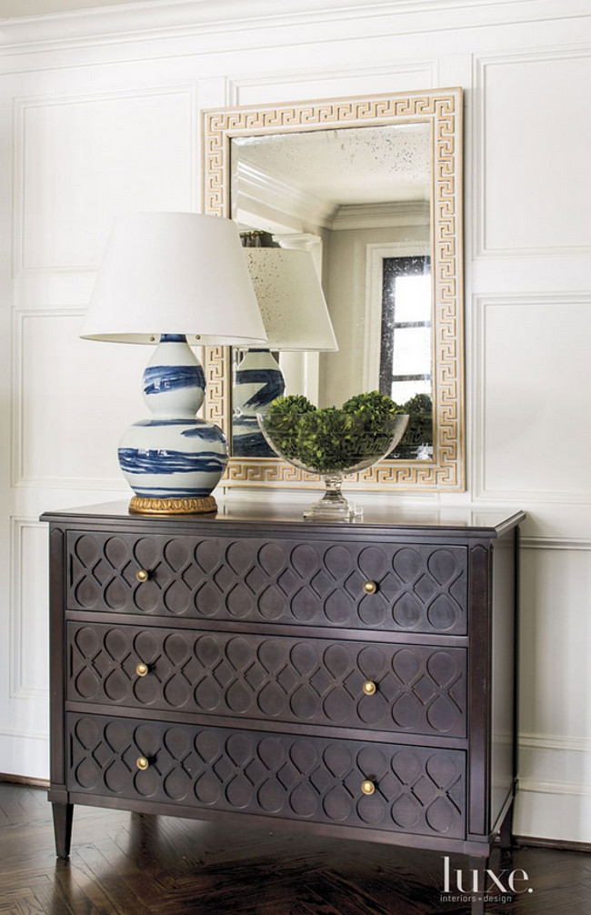 Classic foyer design. The foyer’s Pane e Vino server and classic brushstroke lamp are by Bunny Williams Home. A Hickory Chair chest, Phillips Scott Greek key mirror, and Bunny Williams lamp add interest, as does the room’s herringbone wood flooring. Herringbone Foyer Flooring Beth Gularson.