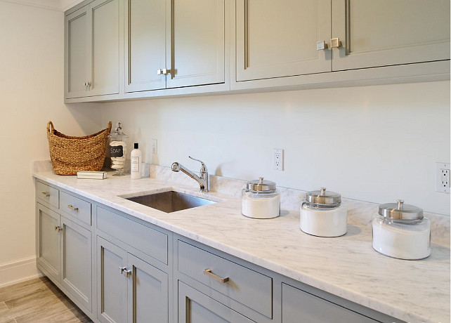 Laundry Room cabinet and countertop. Laundry room with gray cabinets paired with carrera marble countertops. Laundry room features square sink as well as vintage canisters. #LaundryRoom #Countertop #Cabinet Blue Water Home Builders.