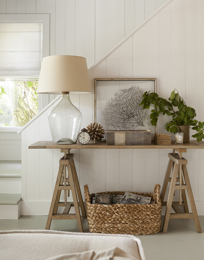 Foyer Decor Coastal Cottage Foyer. Cottage foyer is filled with a seagrass basket filled with magazines tucked under wood sawhorse table with smoke gray glass lamp, framed sea fan #Cottage #Foyer Jenny Wolf Interiors