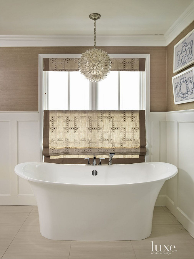 Master Bathroom Ideas. The master bathroom is clad in new wainscoting and Phillip Jeffries wallpaper. Custom window treatments lend warmth to the room; the Worlds Away Venus Capiz Pendant light adds elegance to this bathroom. #MasterBathroom GR Interiors.