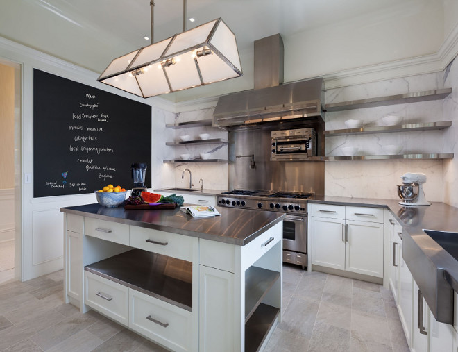 Modern KItchen with Chalk Board. This modern kitchen features a chalk board, marble slab backsplash, stainless steel countertop and floating shelves on both sides of rangle hood. #Modern #Kitchen #ChalkBoard #FloatingShelves #StainlesssteelCounbtertop Sotheby's Homes.