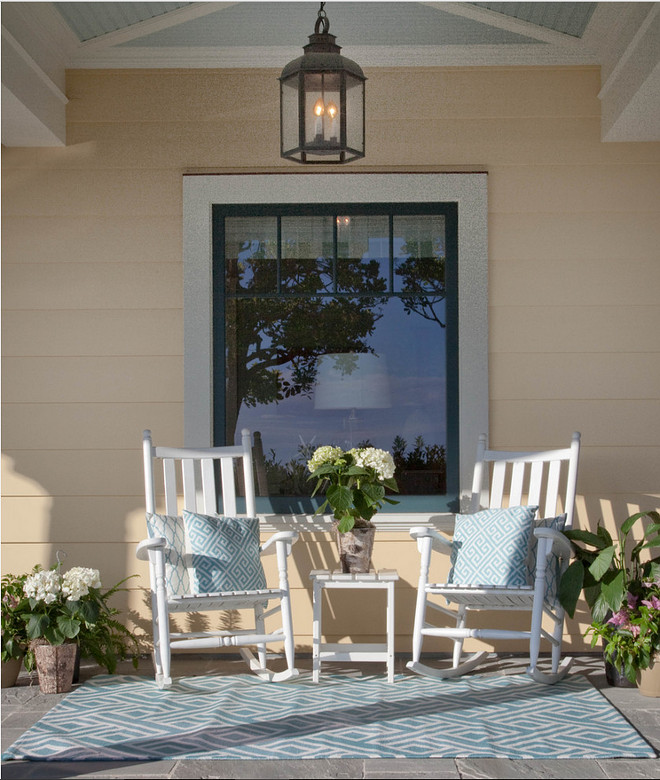 Beach house front porch with white rocking chairs, blue turquoise pillows, light blue outdoor rug and a lantern pendant hung from the blue ceiling. #porch Kim Grant Design Inc.