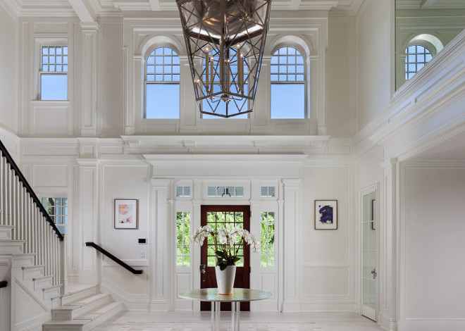 Benjamin Moore China White. This impressive two story foyer is painted in Benjamin Moore China White. Notice the detailed wainscoted staircase and ceiling. #BenjaminMooreChinaWhite #Foyer #Windows
