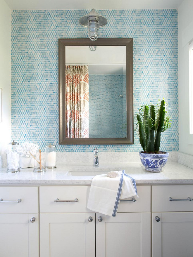 Bathroom Blue tiles. A handsome framed mirror creates a focal point behind the vanity, and contrast for the surrounding blue tiles and white ceiling and walls.