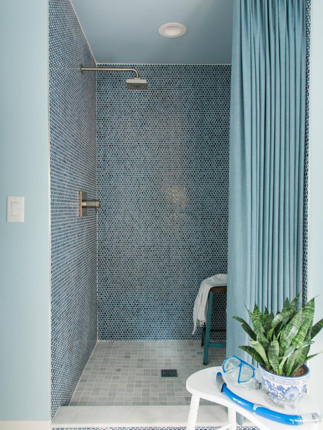 Cobalt blue penny round tiles with contrasting white grout lines the interior of the shower. It lends a beachy feel to the room and pairs well with the French blue painted walls of the space.