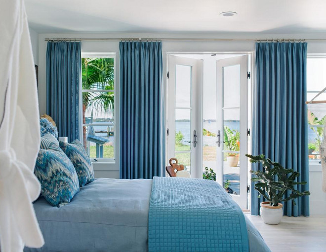 This bedroom suite has French doors that open out on to a terrace. The blue-gray linen draperies frame the view of the yard and nearby river.