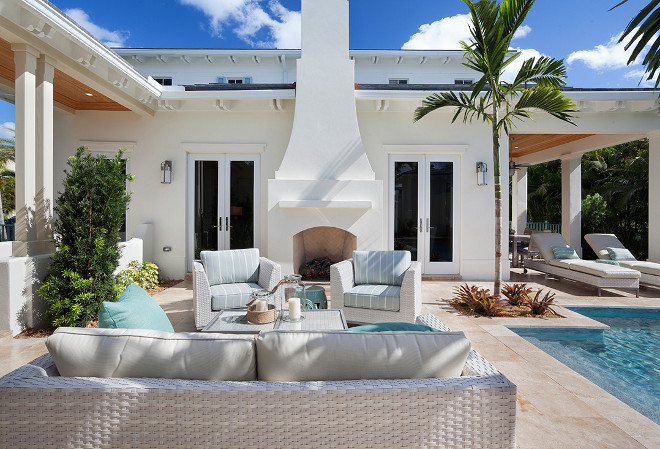 Outdoor lounge area and fireplace with white wicker furniture. #Outdoors #loungearea #fireplace Casatopia, LLC - Ibi Designs