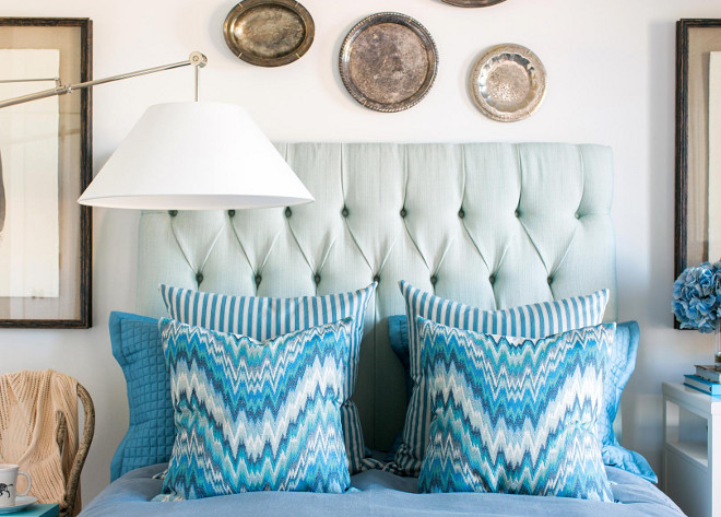 The soft white walls, ceiling and trim is the perfect back drop for the sea foam green, linen tufted headboard. Pops of bold color stand out in the classic flame stitch and ticking stripe pillows.