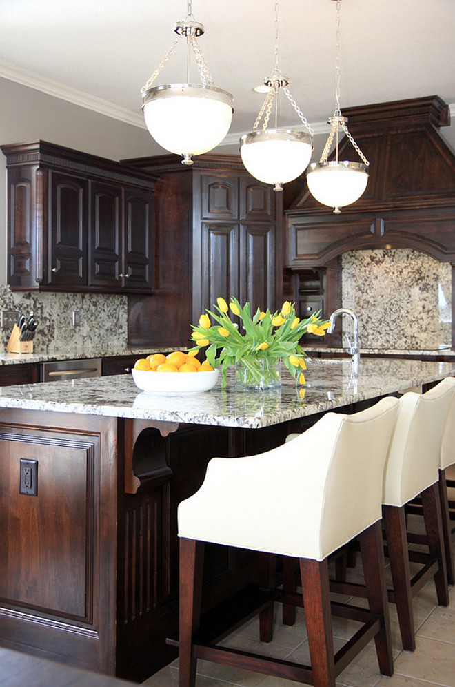 How to change your dark-stained kitchen cabinets without painting them. The designer updated this kitchen by only changing the old counters and backsplash for granite. This is a good idea if you're trying to sell your home and do a quick kitchen reno before putting it on the market.#darkstainedcabinet #kitchenreno Bria Hammel Interiors