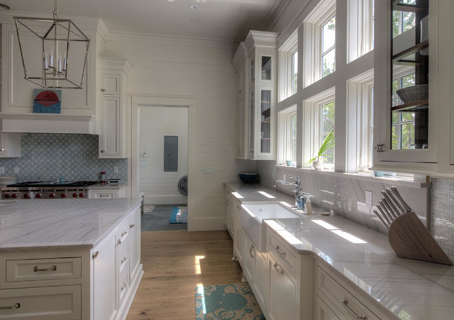 Kitchen with white shiplap walls, beached white plank floors, white marble countertops and blue and white mosaic tile backsplash. 30A Interiors