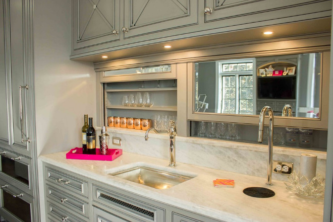 Butlers pantry cabinet door ideas. This kitchen bar has remote-controlled retracting mirrored doors where glassware is stored. Above, a bar sink and a sleek, concealed Top Brewer coffeemaker is placed on an elegant marble countertop.  #Butlerspantry #bar #cabinet #butlerspantrycabinet #Barcabinet #kitchen Lori Wiles Design