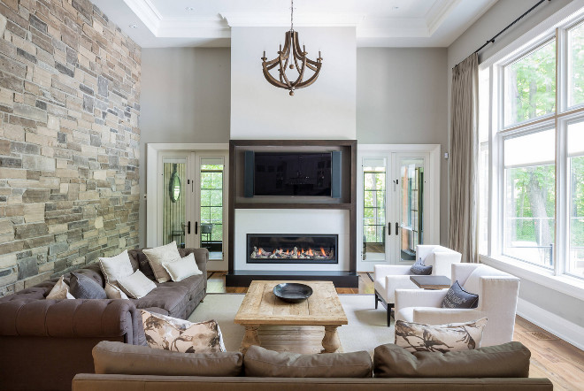 Family Room Stone Wall Ideas. Family Room Stone Wall. Family Room with accent stone wall. Family room features stone wall, tray ceiling, floor to ceiling windows and wood chandelier. #FamilyRoom #StoneWall #Familyroomstonewall David Small Designs