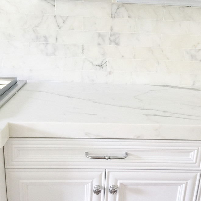 White kitchen cabinets painted in white lacquer with no pigment in it, semi gloss sheen and Calcutta marble, 3″x12″ subway tiles with white grout for the kitchen backsplash. For the island and counters I picked a 2″,honed Calcutta marble with a clean, mitered edge. Restoration Hardware silver pulls and knobs blended well with the cool tones in the marble. #kitchen #marble #backsplash #countertop #knobs #pulls #hardware Becki Owens