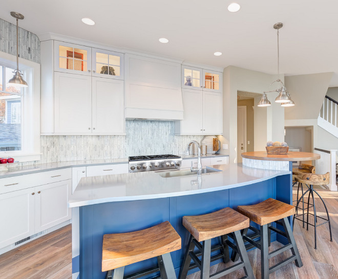 White crisp cabinets set the casual tone alongside durable, low-maintenance Quartz countertops and a vibrant blue island that becomes a fun and functional focal point for the light-filled space. Mosaic glass tiles adorn the backsplash and the adjacent living room fireplace for a more cohesive feel.