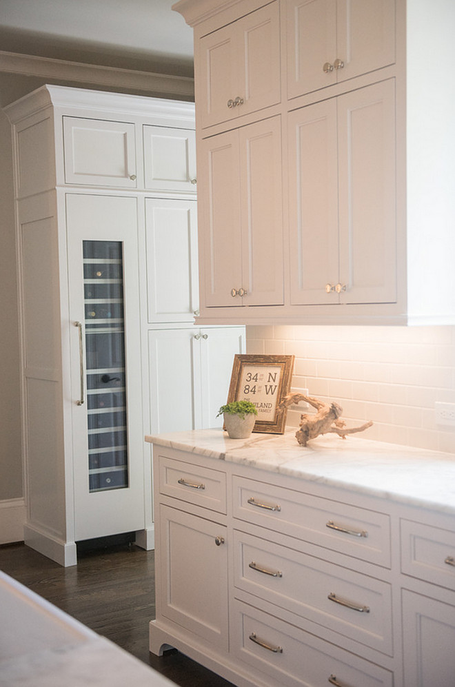Classic kitchen elements. Kitchen features classic white cabinets, white marble countertop, white subway tile backsplash, polished nickel hardware and dark stained wood floors. Artisan Design Studio