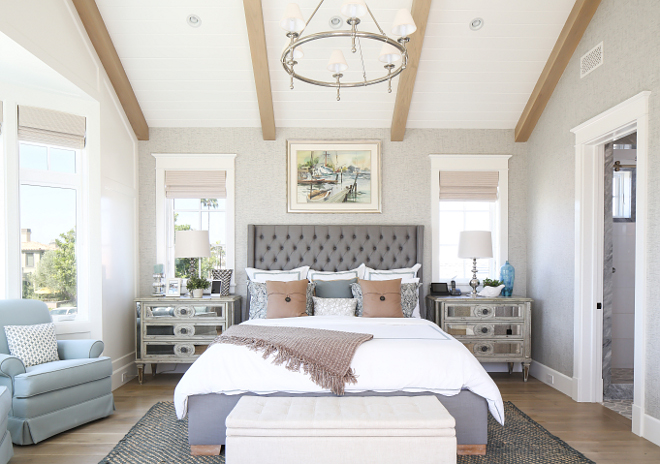 Bedroom. 21. This master bedroom features textured gray wallpaper, vaulted ceilings with exposed beams, light color wood floor and an elegant tufted headboard flanked by mirrored night stands. #bedroom Patterson Custom Homes. Interiors by Trish Steele, Churchill Design.