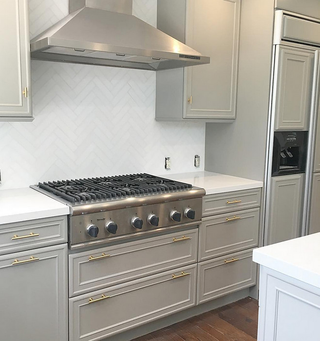 Dovetail SW 7018 by Sherwin-Williams. Dark grey kitchen cabinets painted in Dovetail SW 7018 by Sherwin-Williams with brass hardware and herringbone marble tile backsplash. #DovetailSW7018SherwinWilliams. Eye for the Pretty. 