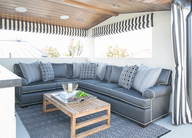 Deck furniture ideas. The deck also features a gray roll-arm sectional with white piping facing a teak coffee table atop a black and white diamond print rug. #deck #outdoorfurniture #outdoors Patterson Custom Homes