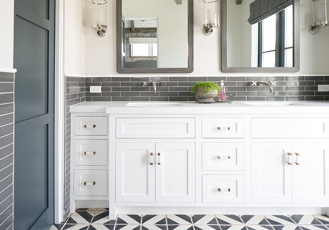 The master bathroom features white dual washstand fitted with his and her sinks positioned under wall-mount sinks and gray distressed mirrors illuminated by nickel and glass sconces from Circa Lighting. Patterson Custom Homes