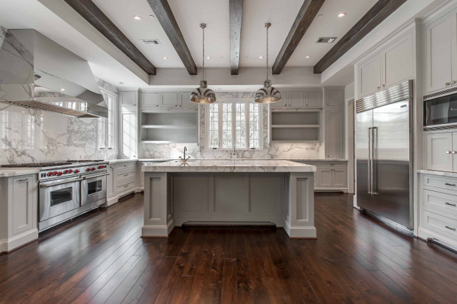 Gray kitchen with pale gray cabinets and white marble slab countertop and backsplash and ceiling beams. #kitchen #graykitchen #palegray #kitchencabinets #beams Elizabeth Garrett Interiors.