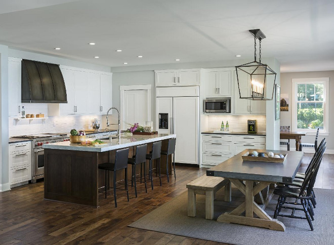 Transitional kitchen opens to dining room with Darlana Linear Chandelier and Restoration Hardware Zinc top dining table. The perimeter counters are honed Soap Stone (charcoal tones) and the island is Carrera Marble with a mitered 3.5" edge. #OpenKitchen #DarlanaLinearChandelier #Zinctable #kitchen Charlie & Co. Design, Ltd. Hagstrom Builders. 