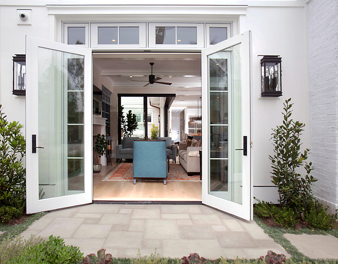 Famrily room French Doors. Take a peek into the great room through these gorgeous french doors made by JeldWen. Wall-mounted lanterns are Troy Lighting ( 11”W, 24”H) in hand-forged iron. Entry includes white washed pacific stone pavers laid in an ashlar pattern. #FrenchDoors #FamilyroomDoors #Familyroom 
