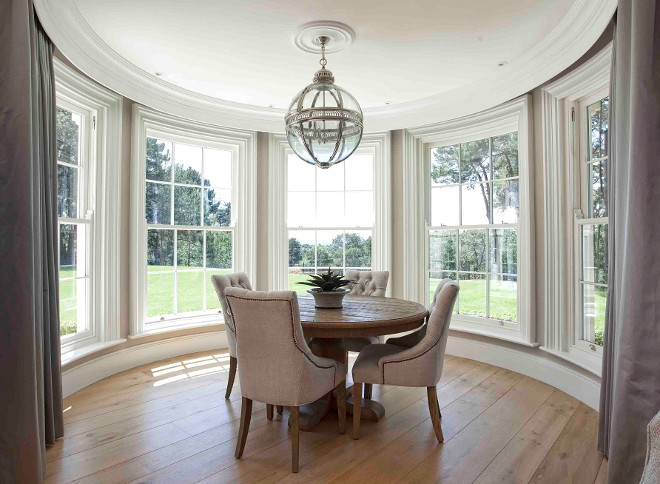 Breakfast room. Curved breakfast room. The curved sliding sash windows make a beautiful backdrop in this dining area. The curved windows are dressed in grays curtains with drapery hardware hidden behind built-in crown moldings. #breakfastroom #Curvedwindows #CurvedBreakfastroom Hayburn & Co. 