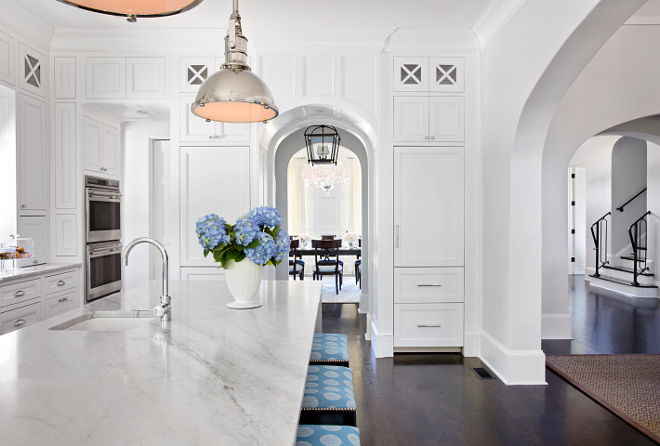 Two refrigerators in kitchen. This stunning white kitchen features a small prep sink on the island and white wood paneled refrigerators flanked by arched doorway. #tworefrigerators #kitchen #archway #arch TS Adams Studio Architects. Traci Rhoads Interiors.