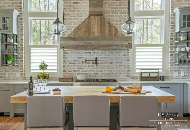 Kitchen with exposed brick backsplash, exposed brick walls and kitchen hood made of reclaimed wood planks. Kitchen cabinet paint color is SW Dorian Gray. TS Adams Studio Architects Inc.