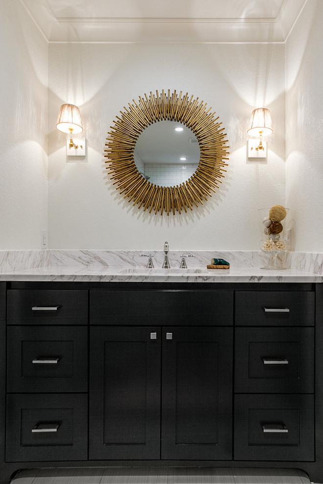 Bathroom with black cabinetry, brass mirror and brass lighting. The countertop is a Volakas 3cm polished marble slab. Mirror is from Arteriors Home - the Prescott Round Mirror. #Bathroom #Brassmirror #mirror #lighting #bathroomlighting Redo