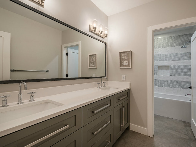 Grey bathroom vanity, extra wide cabinet pulls, concrete flooring and white quartz countertop. Northstar Builders, Inc.
