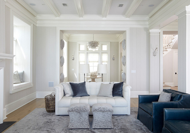 Living room. Living room features an ivory coffered ceiling, with coffers painted white, accented with a modern brown ceiling fan creating a cool breeze over white tufted roll arm sofas lined with blue pillows facing each other across from an industrial coffee table. A pair of blue accent chairs face a white shiplap fireplace wall fitted with a flat panel tv over a white fireplace mantel finished with a black stone surround flanked by window seat alcoves. #livingroom TS Adams Studio Architects. Laura Allyson Interiors.