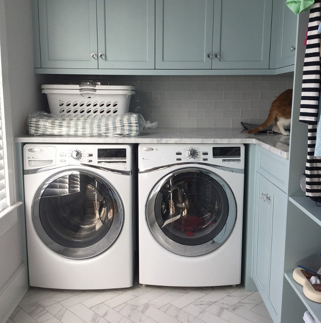 Vervain Blue by Benjamin Moore. This laundry room is such a functional space! Cabinets are painted Vervain Blue by Benjamin Moore. Tile is a 6x12 in a herringbone pattern. Vervain Blue by Benjamin Moore. Blue laundry room cabinet paint color. Vervain Blue by Benjamin Moore #VervainBluebyBenjaminMoore #Bluelaundryroomcabinetpaintcolor #laundryroomcabinetpaintcolor #laundryroom #cabinet #paintcolor