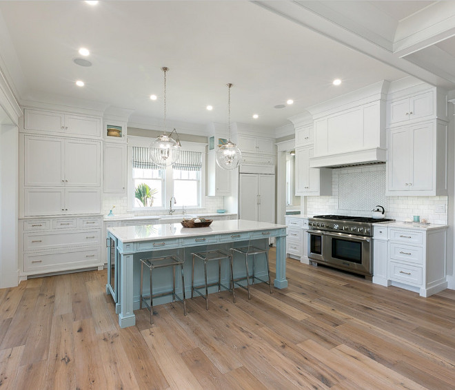 White kitchen that's offset by a Benjamin Moore Vermouth Blue painted island. CB2 acrylic counter stools and custom made pin striped roman shades.