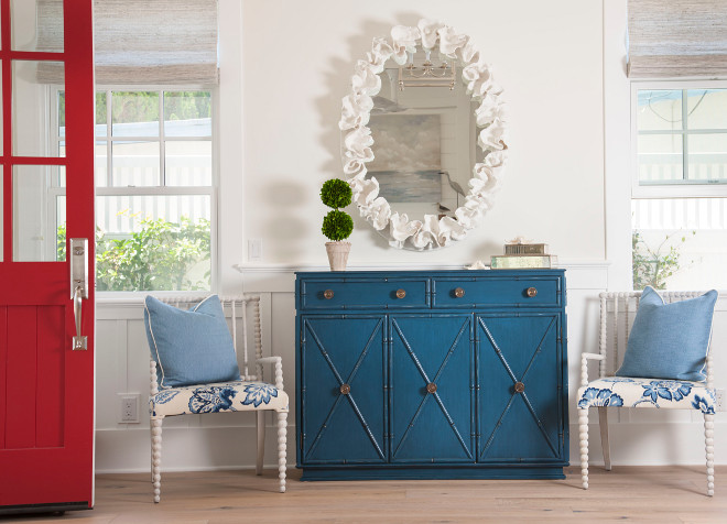 Foyer with red front door and blue and white coastal decor. Classic Americana colors are evident in the foyer. Coastal Americana style. Americana. Coastal foyer with red door. #Reddoor #Americana #Coastal #Foyer #Blueandwhite Flagg Coastal Homes