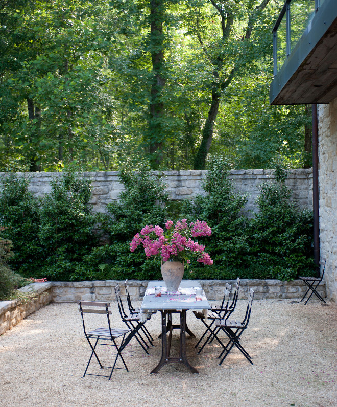 Gravel Patio. French style gravel patio with stone garden walls. Gravel patio with French bistro table in iron and marble lined with delicate slatted wood outdoor dining chairs . #Gravel #patio #FrenchGardens #Gardens #Garden #Stonewall Smith Hanes