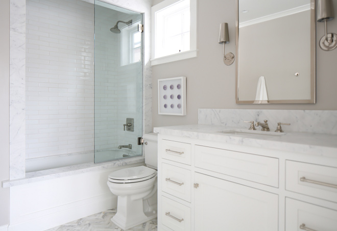 Bathroom tub. Guest Bath Tub: Marble slab surrounds with tub tob, wood accent front panel and 2x4 white hand pressed subway tile. Sconces are from "Restoration Hardware Modern". Winkle Custom Homes. Melissa Morgan Design. Ryan Garvin Photography