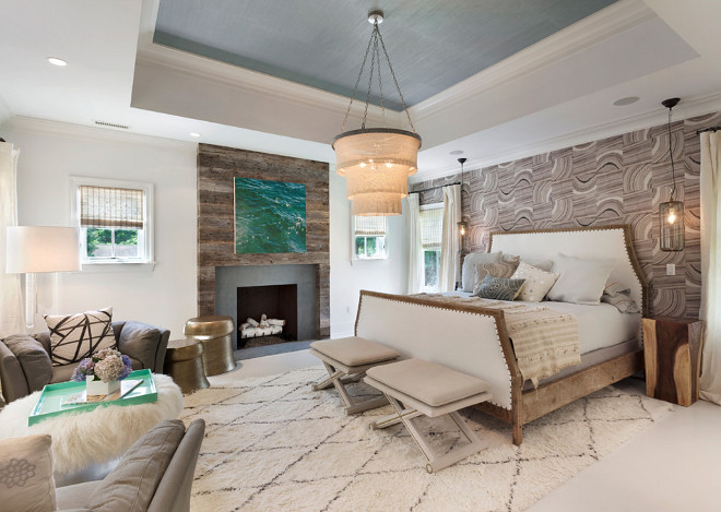 Master Bedroom. Transitional Master Bedroom. The bed chamber features a high tray ceiling and a fireplace with a surround comprised of natural stone and floor to ceiling antique Vermont barn board siding. #Masterbedroom #transitionalmasterbedroom #transitionalbedroom Bluewater Home Builders