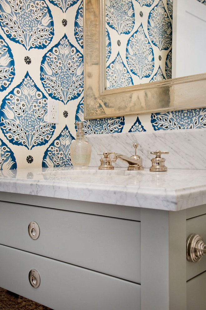 Bathroom Ideas. Bathroom Ideas. Beautiful blue and gray powder room features a gray single washstand fitted with polished nickel hardware and a Carrera marble countertop finished with an oval sink and a polished nickel faucet kit positioned beneath a champagne gold beveled mirror fixed on a wall covered in Galbraith & Paul Lotus Wallpaper. bathroom-ideas #BathroomIdeas