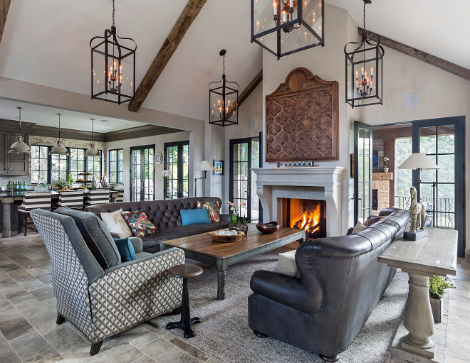 French Country great room. The kitchen opens directly to a great room with cathedral ceiling with reclaimed beams. Lanterns are Bradford Lantern from Troy lighting. Furniture is from Restoration Hardware. Mantel is Cast Limestone #greatroom #FrenchCountry #beams Hendel Homes 