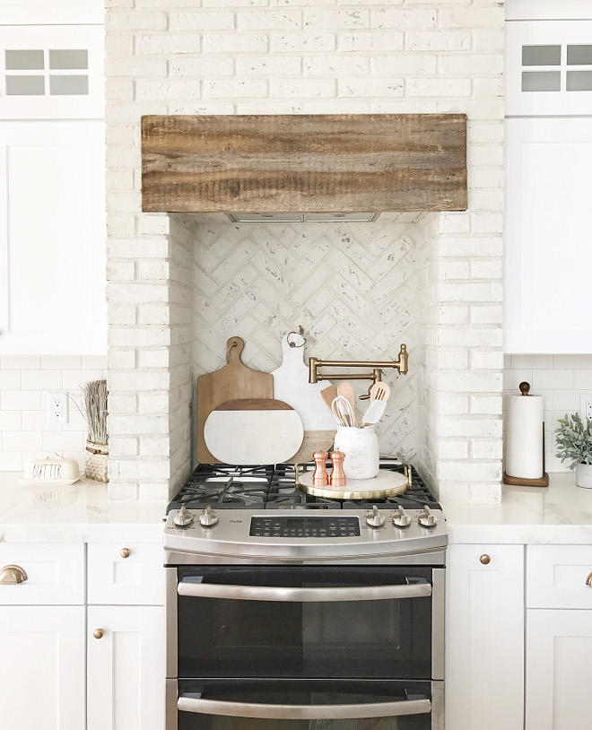 Kitchen brick hood and kitchen brick backsplash. Using distressed painted brick in kitchens is a trend that is here to stay. I love that Nina chose to use the painted brick in a herringbone pattern behind the stove. #kitchenbrick #brickhood #brickbacksplash #distressedpaintedbrick #paintedbrick #whitebrick #brick #herringbonebrick #farmhousekitchen Beautiful Homes of Instagram @nc_homedesign via Home Bunch