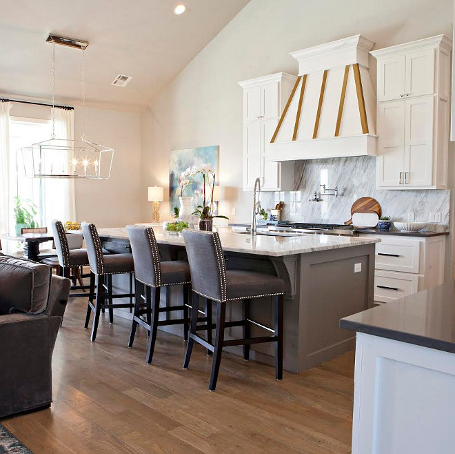 Kitchen. The kitchen was thoughtfully done by our clients. The backslash and countertops are both in a beautiful marble. The hardware adds a modern touch, with the polished nickel pulls and knobs on the cabinetry. The oven hood range is accented beautifully in white and gold. The bar stools were previously purchased from the clients. They have a dry bar off the kitchen with glass cabinetry. We decided to fill the shelves with blue and white, so that it creates a neutral balance with the colorful space. kitchen-island #kitchen Ivy House Interiors