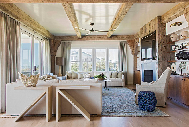 Living room. Rustic living room. Blue hues play perfectly along the neutral color palette found in this room. Pecky Cypress wood surrounds the fireplace, complementing the reclaimed ceiling beams. 
