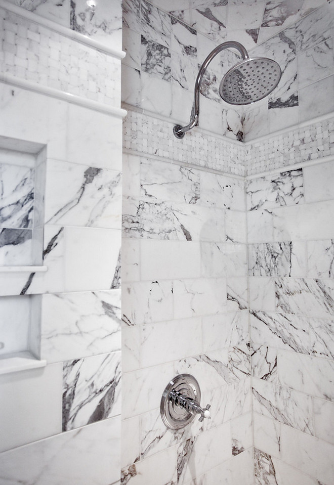 Shower fixtures. A view of this custom shower made from a design mixture of large marble subway tiles, small basket weave, and upper square tiles. Chrome rainhead shower with trim and built-in niche. shower #showerfixture Karr Bick Kitchen and Bath