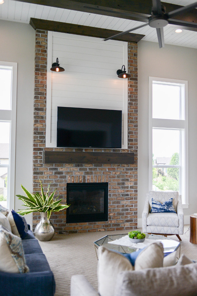 Farmhouse Fireplace. This farmhouse-inspired fireplace features brick, shiplap and barn lighting. #FarmhouseFireplace #Farmhouse #Fireplace #brick #shiplap #barnlighting #barnlight Millhaven Homes
