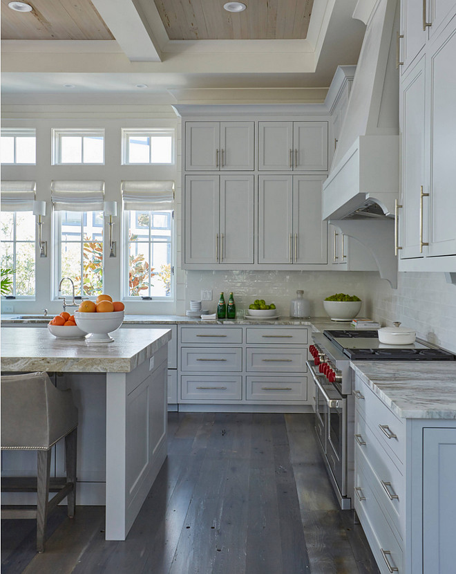 Stacked Kitchen Cabinets with Rustic Wood Floors. Stacked Kitchen Cabinets with Rustic Wood Floors. The kitchen features light gray stacked cabinets adorned with long satin nickel pulls paired with quartzite countertops and a light gray glazed tiled backsplash. The rustic wood floors are custom dark stained. #rusticflooring #rusticwoodfloors #StackedKitchenCabinets #RusticWoodFloors #rusticwood #rusticplankfloor grey-brown-hardwood-floor Geoff Chick & Associates